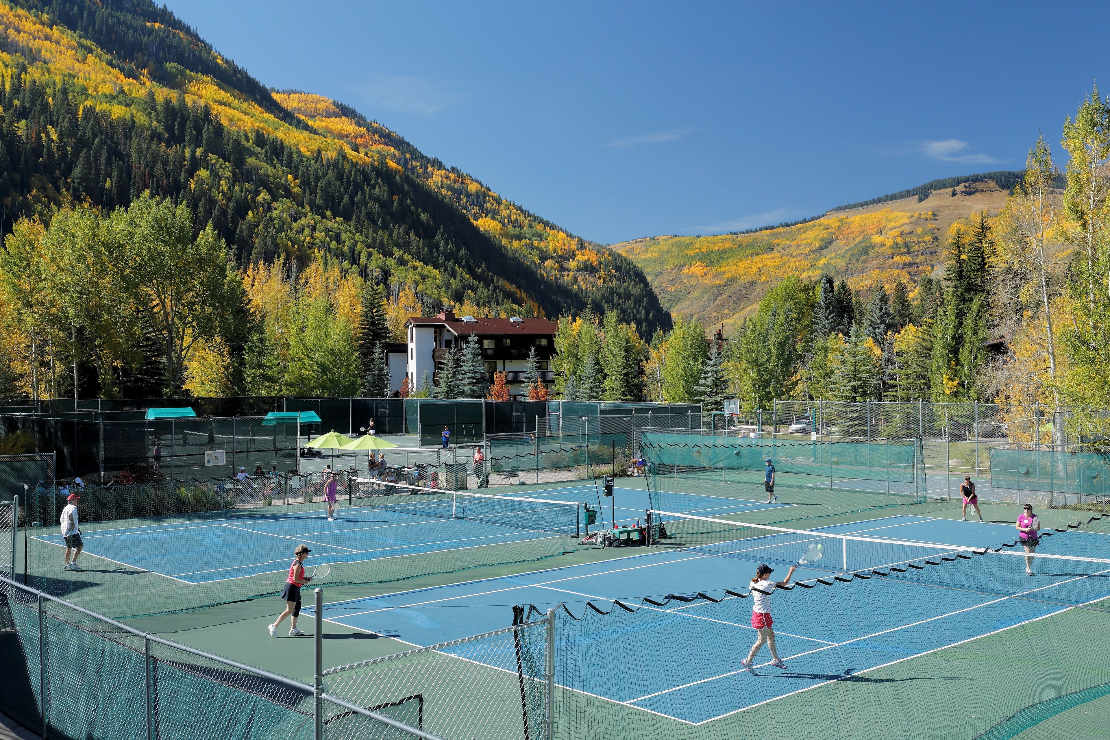 Un campo da tennis all'aperto circondato da una zona montuosa e boscosa.