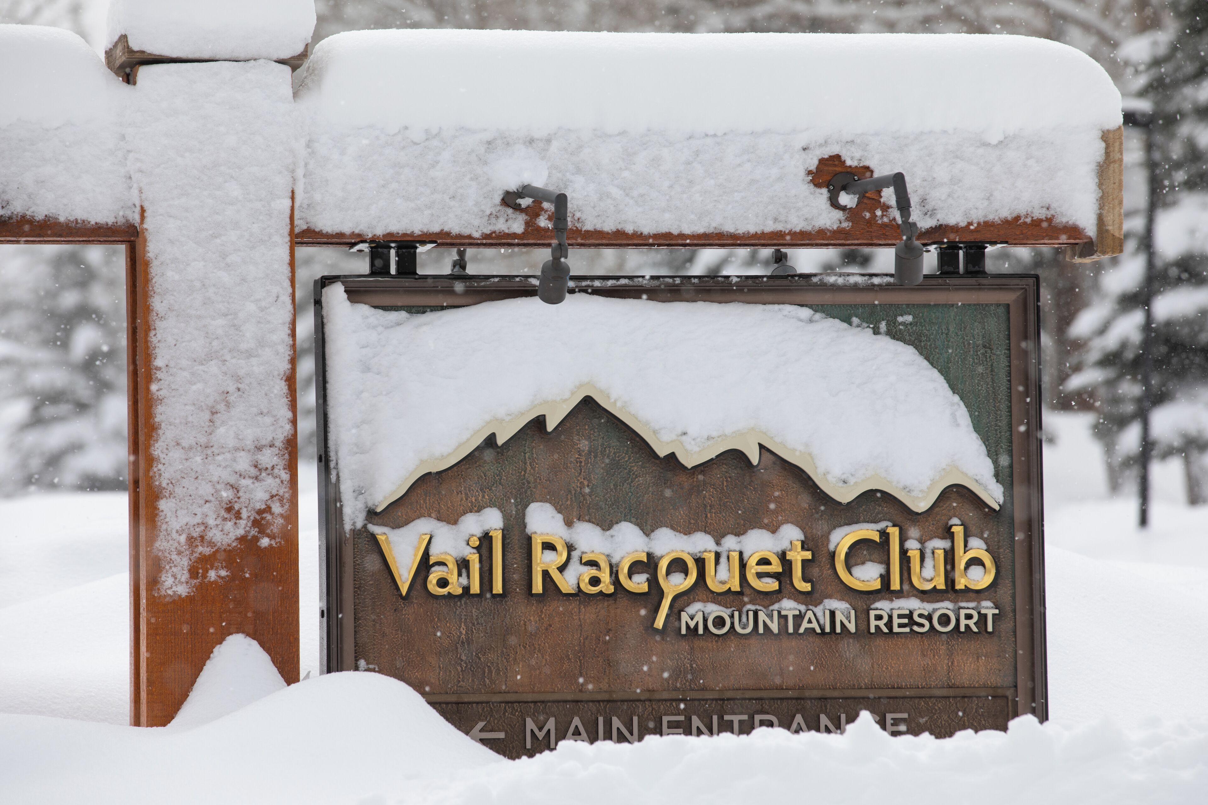 A snow-covered sign for Vail Racquet Club Mountain Resort.