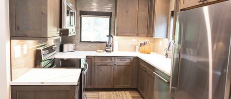 A modern kitchen with wooden cabinets, stainless steel appliances, and a central island.