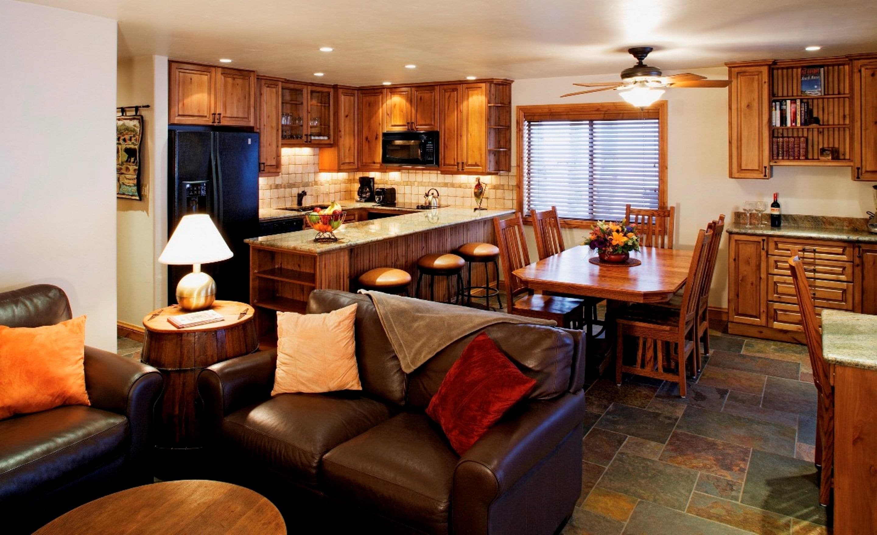 A modern kitchen with wooden cabinets, a central island, and a dining area with a table and chairs.