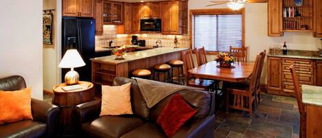 A modern kitchen with wooden cabinets, a central island, and a dining area with a table and chairs.