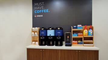 Una estación de café con varios dispensadores, un cartel que dice 'MUST HAVE COFFEE' y varios productos de café en estantes.