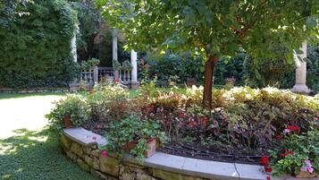 Un jardin bordé de pierres, avec différentes espèces de plantes et une structure en forme de pergola.