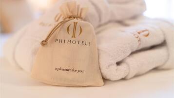 Una borsa con coulisse con marchio PHIHOTELS e asciugamani piegati su un letto.