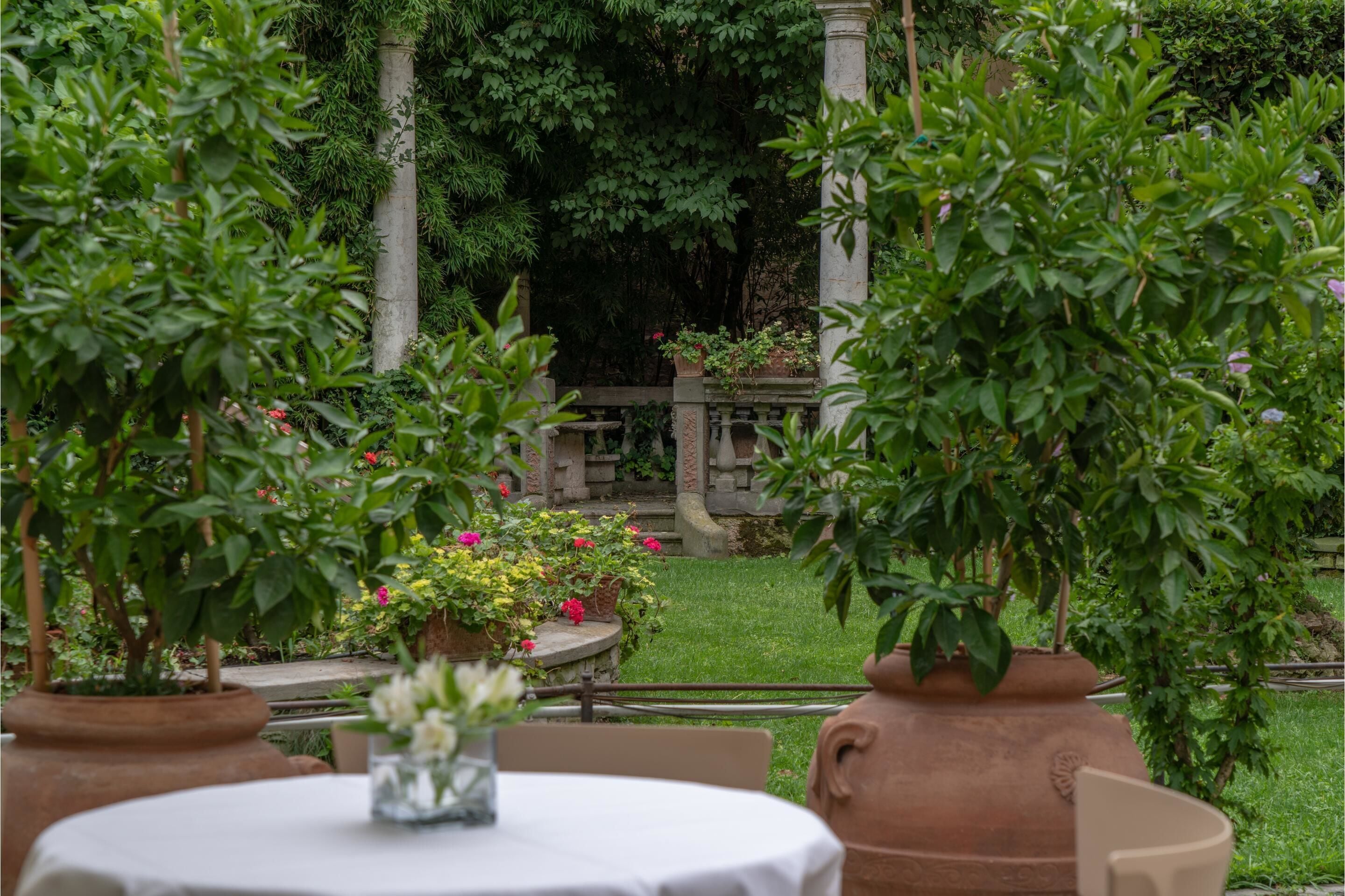 A garden patio with a round table, chairs, and potted plants.