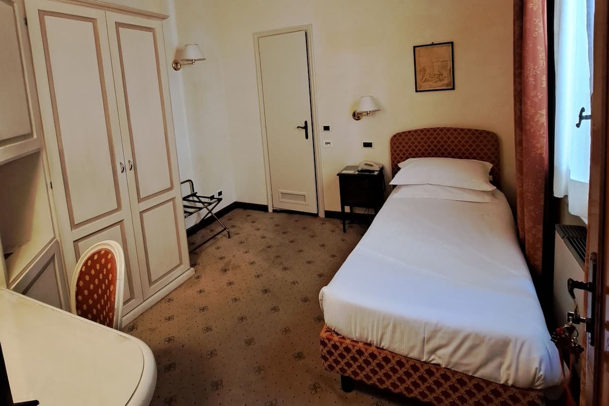 Una habitación de hotel con cama, escritorio, armario y puerta.