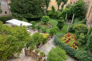 Un patio con jardín central, senderos de piedra y plantas en macetas.