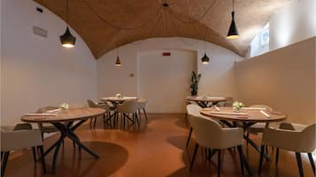 Un comedor moderno con mesas y sillas redondas, techo de madera e iluminación colgante.