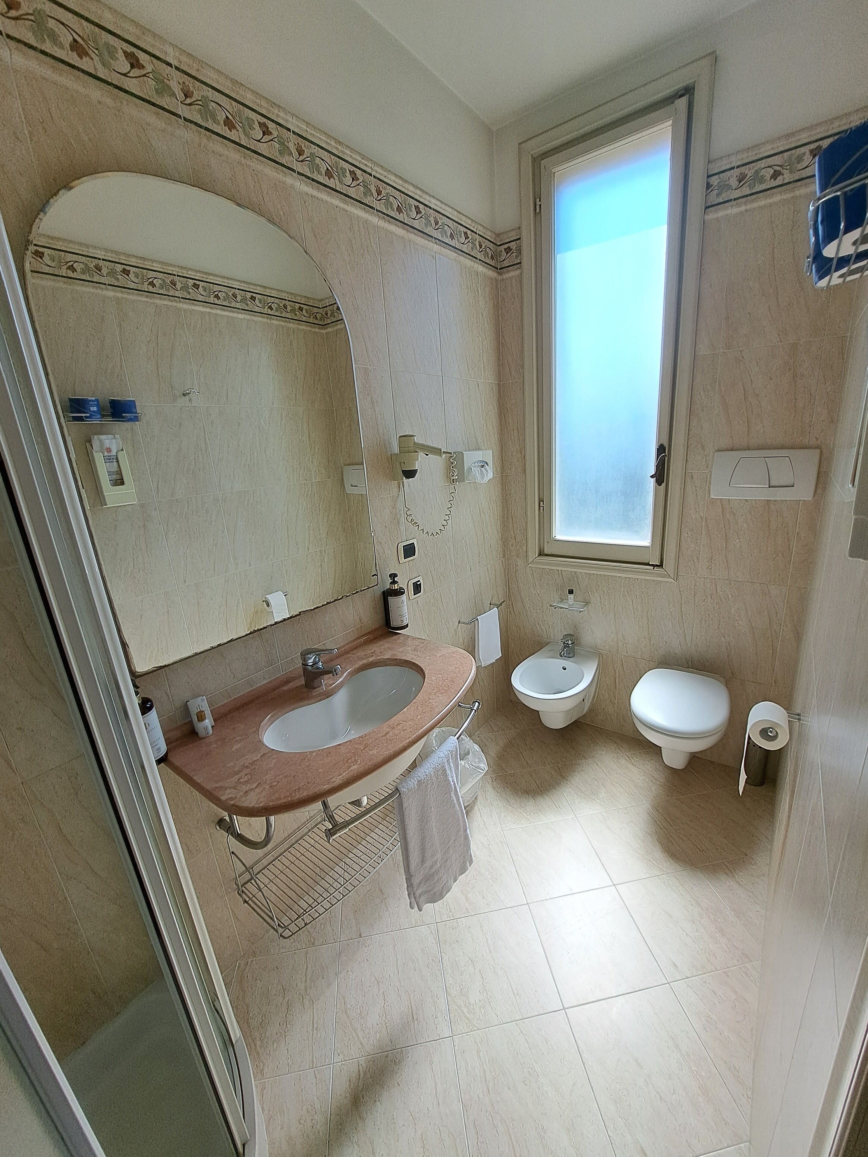 Un baño con lavamanos, bidé, inodoro y ventana.