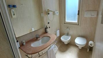 Un baño con lavamanos, bidé, inodoro y ventana.
