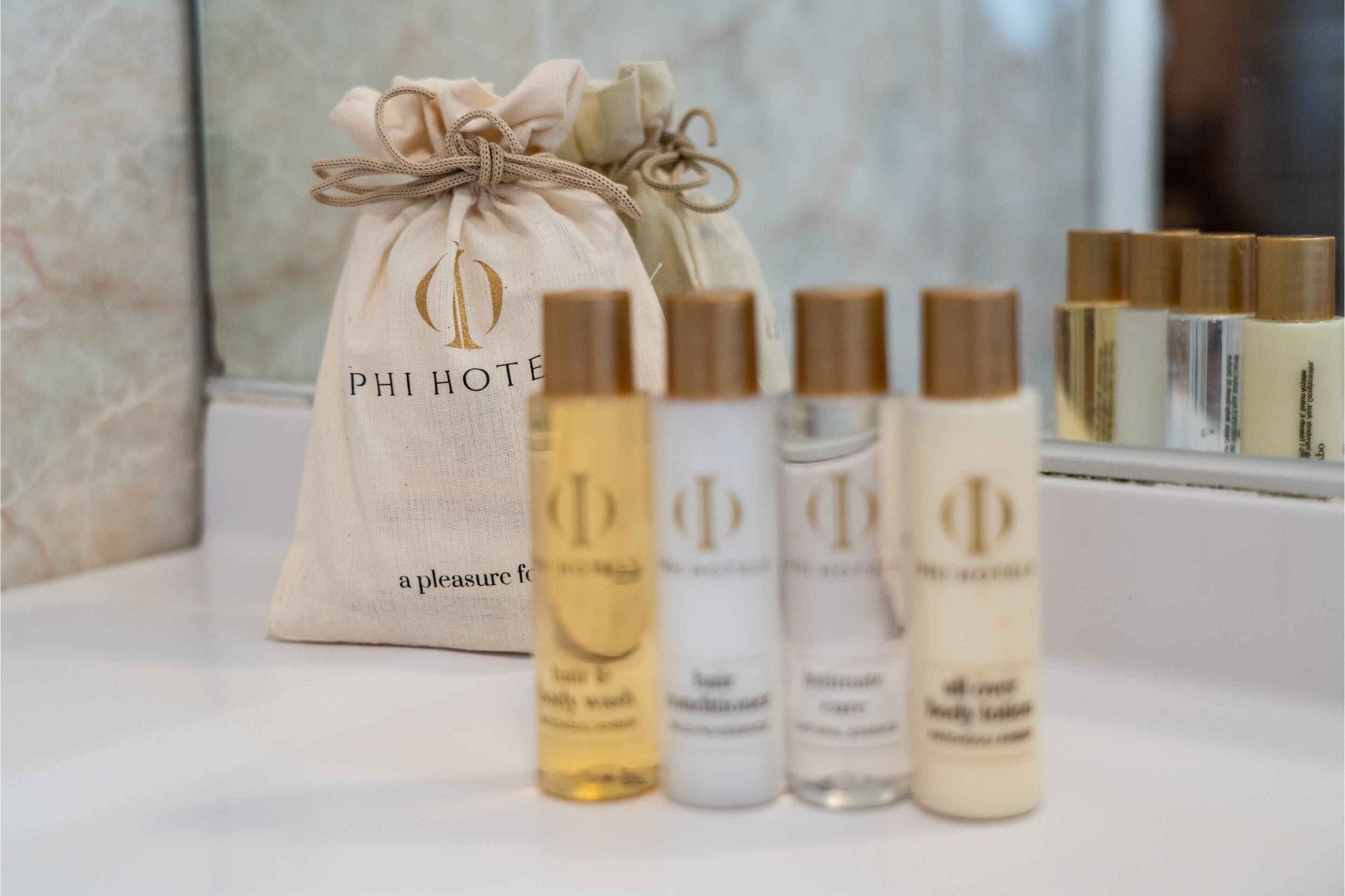 A Phi Hotel gift bag and a selection of body care products on a counter.