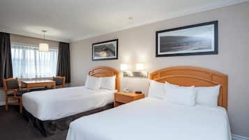 A hotel room with two beds, a desk, and a chair.