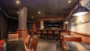 A restaurant with booths and high tables, a bar area, and a mural on the wall.