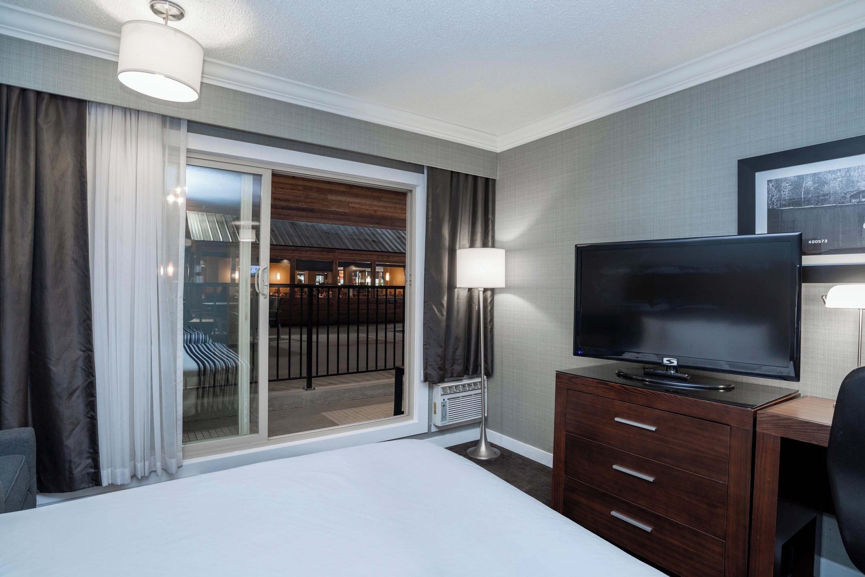 Une chambre d’hôtel avec un lit, une télévision, un bureau et une vue sur l’extérieur.