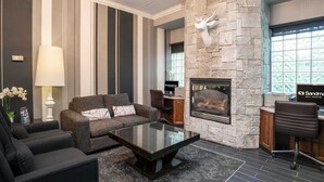 A modern living room with a fireplace, striped walls, and a stone accent wall with a deer head.