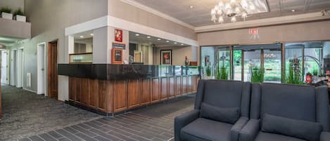 A hotel lobby with a reception desk, seating area, and a view of the outdoors.