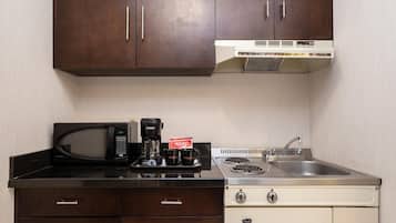 Una cocina compacta con microondas, cafetera y lavamanos.
