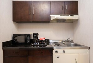 Una cocina compacta con microondas, cafetera y lavamanos.