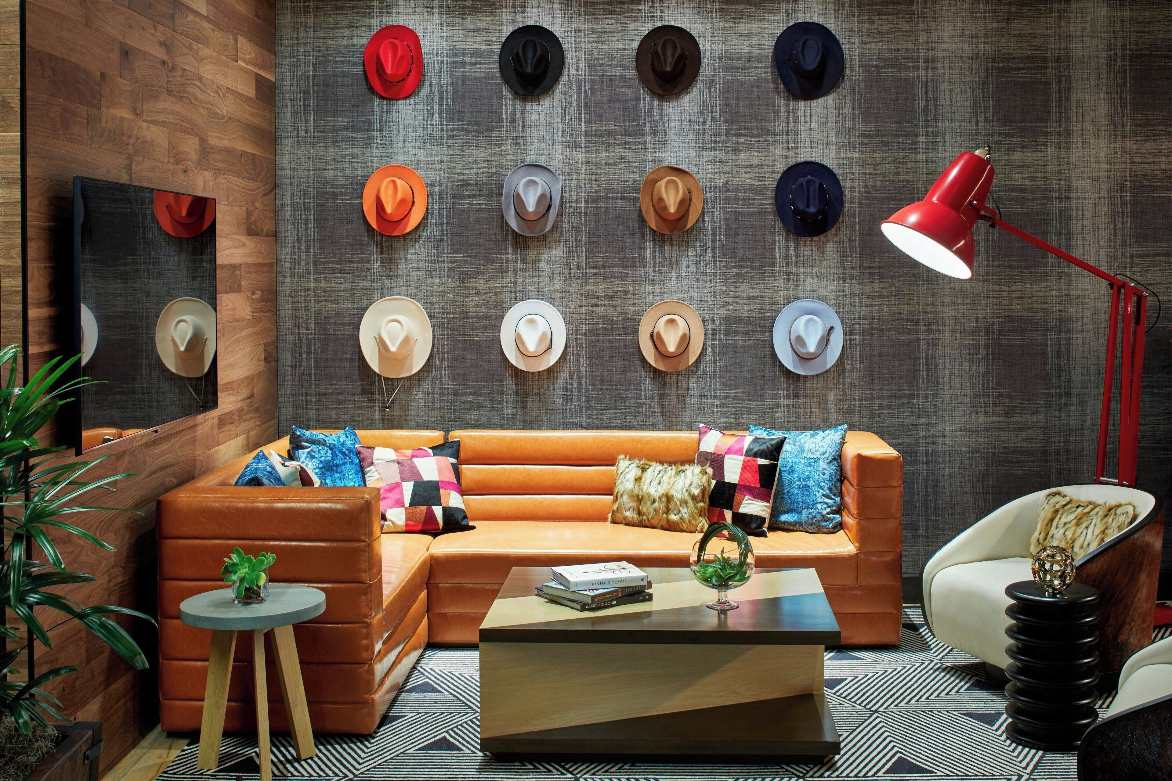 Un salon moderne avec un canapé en cuir, une table basse et un mur décoré de différents chapeaux.