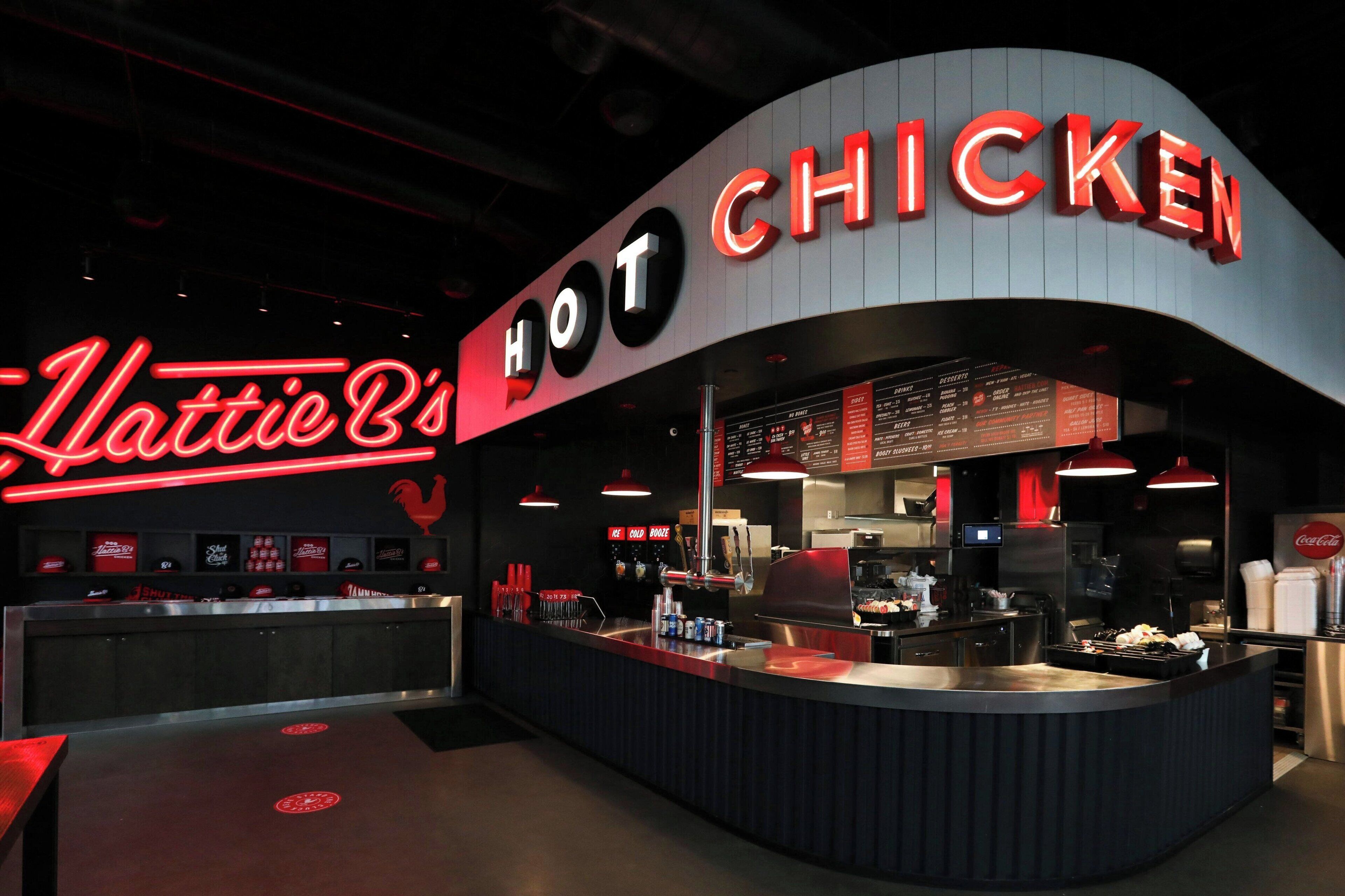 Een restaurant met een gebogen gevel en neonborden waarop 'HOT CHICKEN' en 'Mattie B's' staat.