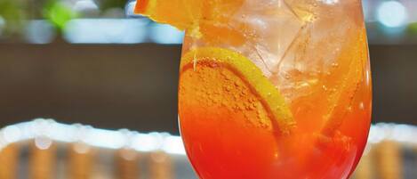 Ein Cocktailglas mit Orangenscheibe am Rand, gefüllt mit Eiswürfeln.