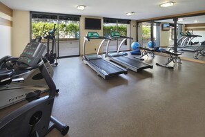 A gym with treadmills, elliptical machines, and exercise balls.