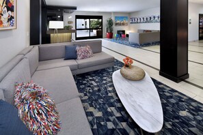 A modern living room with a grey sofa, a coffee table, and a colorful abstract sculpture.