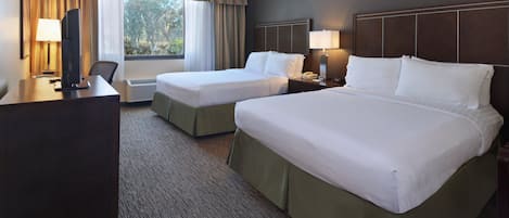 A hotel room with two beds, a desk, a TV, and a window with curtains.