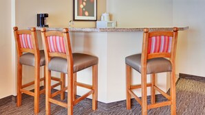 A corner seating area with two wooden chairs with striped cushions, a small bar counter, a coffee machine, and a microwave. - Holiday Inn Hotel & Suites Anaheim by IHG (Anaheim)