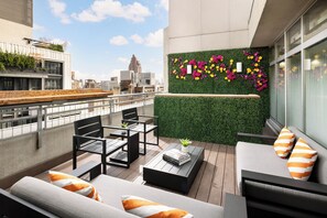 Une terrasse sur le toit avec des sièges extérieurs, un mur végétal orné de fleurs et une vue panoramique sur la ville.