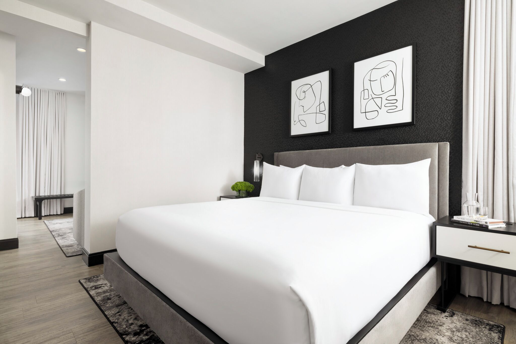 Een moderne slaapkamer met een groot bed, een nachtkastje en twee ingelijste kunstwerken aan de muur.