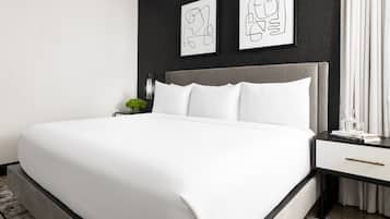 A modern bedroom with a large bed, a grey headboard, and two framed artworks on the wall.