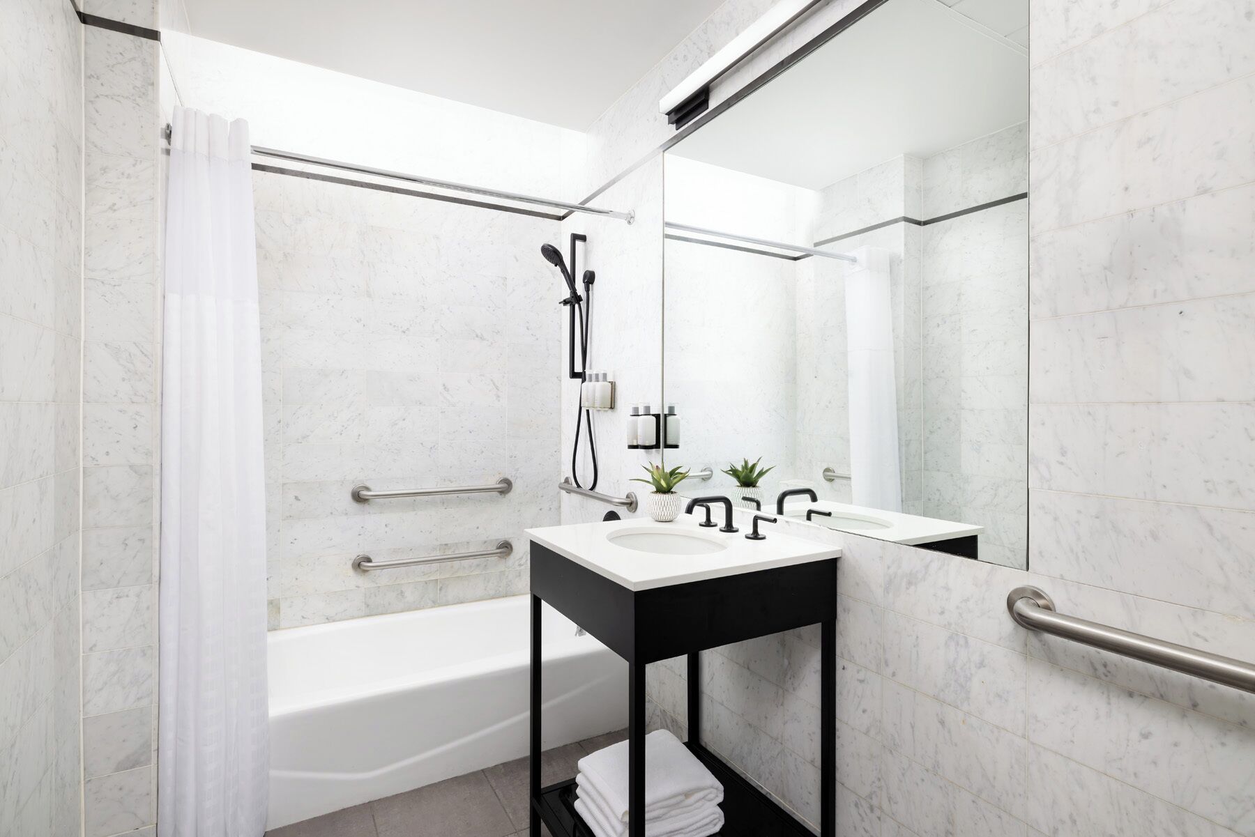 A modern bathroom with a bathtub, a sink with a black countertop, and a mirror.