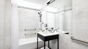 A modern bathroom with a bathtub, a sink with a black countertop, and a mirror.