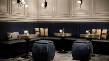 A dark blue upholstered bench seating area with round tables, each with a small vase of flowers.
