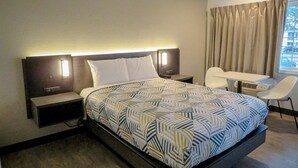 A hotel room with a bed, bedside tables, a desk, and a chair. - Motel 6 Tigard, OR - Portland Southwest (Tigard)