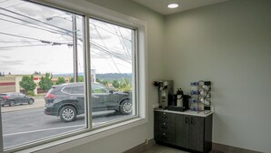 A room with a large window, a coffee machine, and a cabinet. - Motel 6 Tigard, OR - Portland Southwest (Tigard)