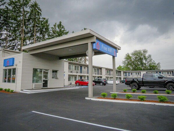 A motel with a covered parking area, a sign indicating free WiFi, and a number 6 sign on the building.