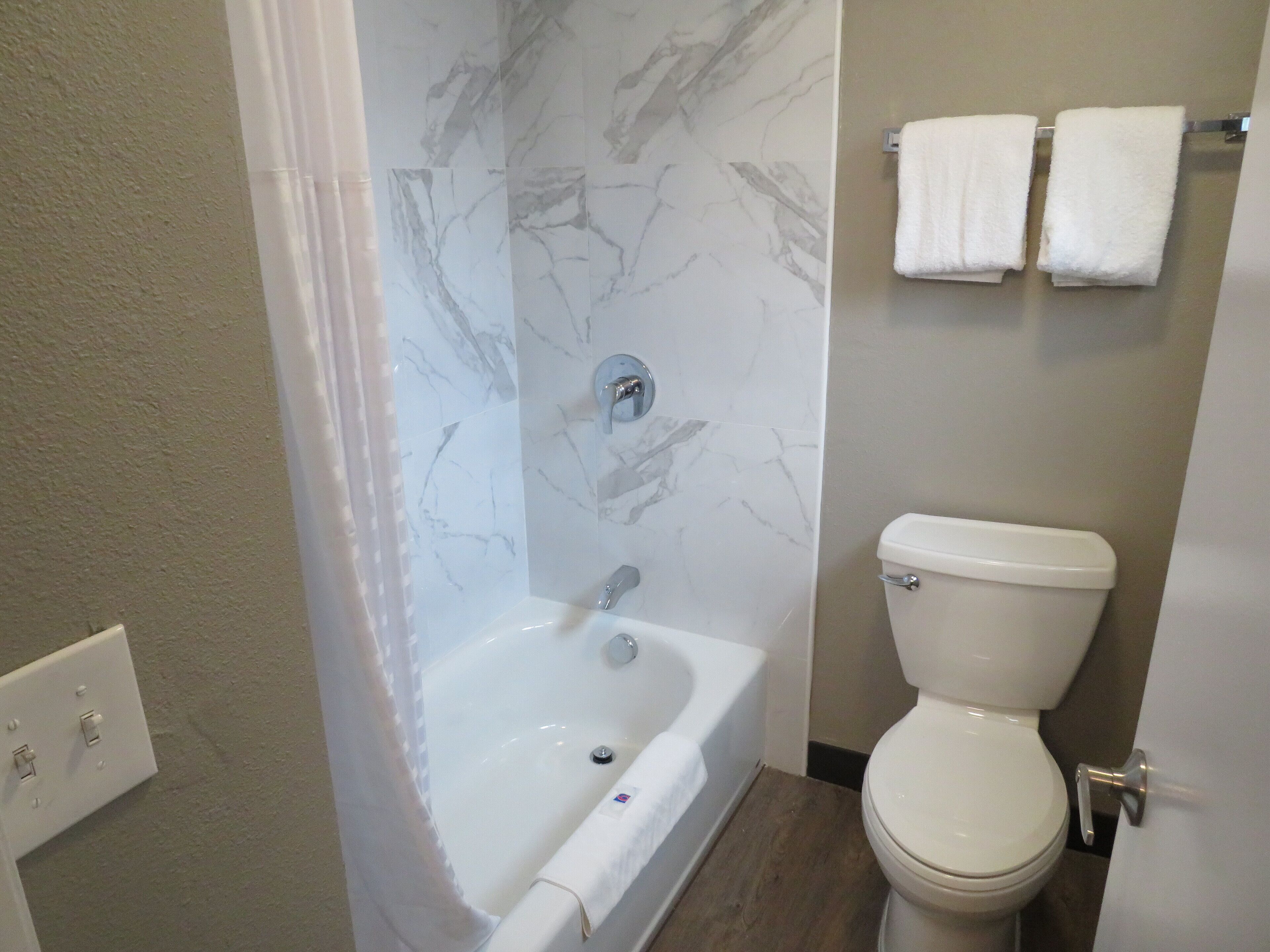Ein Badezimmer mit Badewanne, Toilette und Marmorwänden.