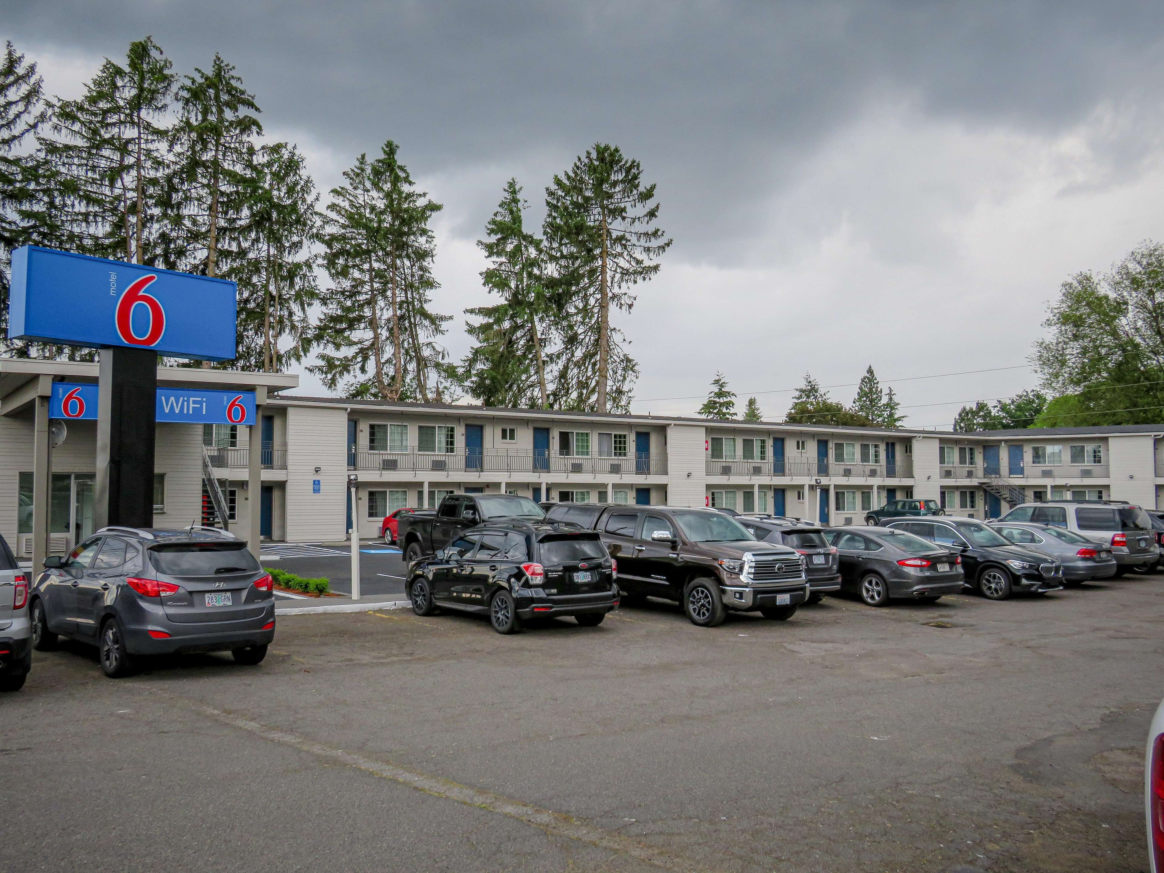 A motel with multiple parking spaces and a large blue sign indicating room number 6.