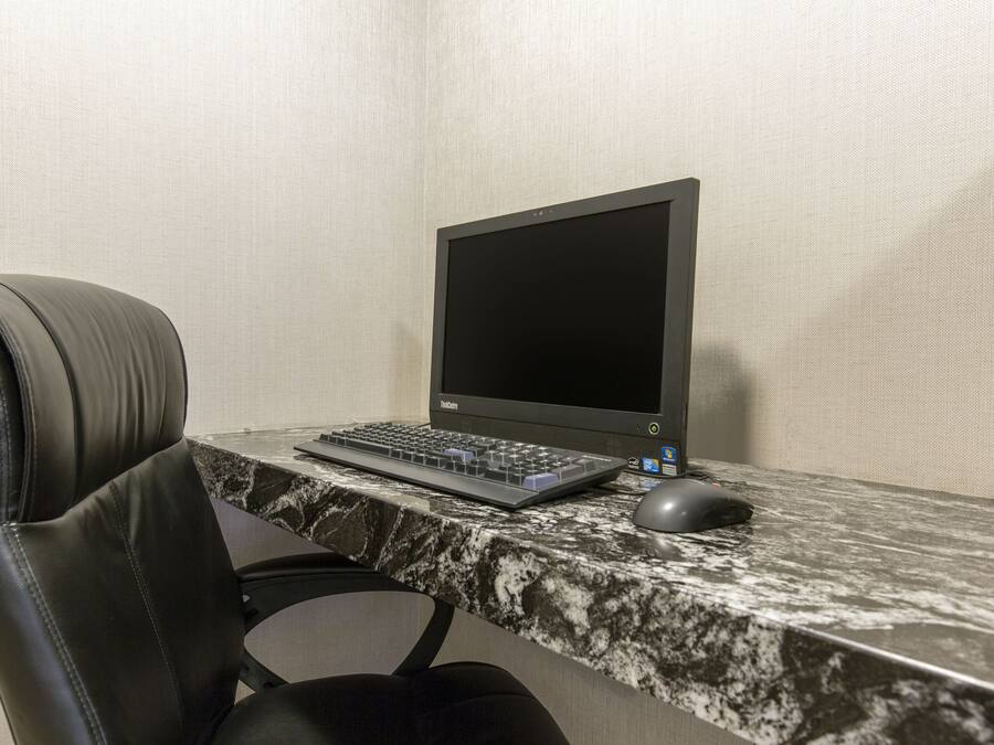 A black leather office chair, a laptop on a marble desk, and a mouse.