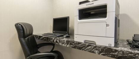 Un espacio de trabajo con una impresora Lexmark, dos monitores y una silla de oficina negra.