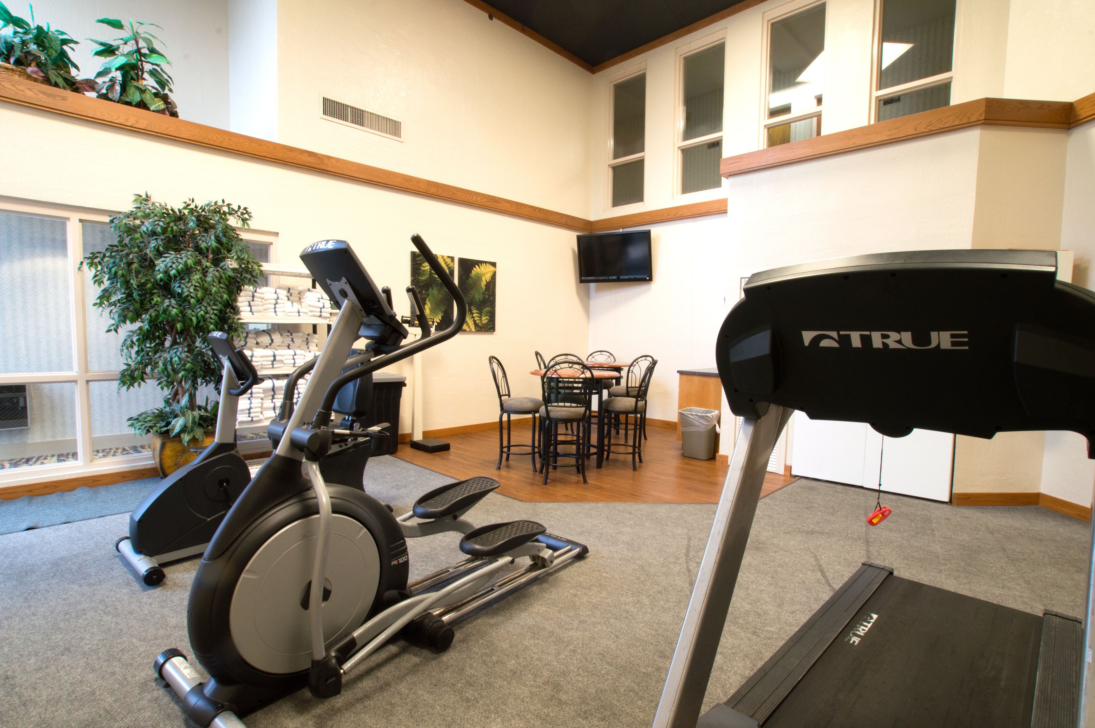 Un gimnasio con equipo de ejercicio, un comedor y un televisor en la pared.