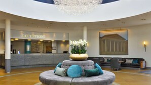 A reception area with a circular seating arrangement, a reception desk, and a large chandelier.