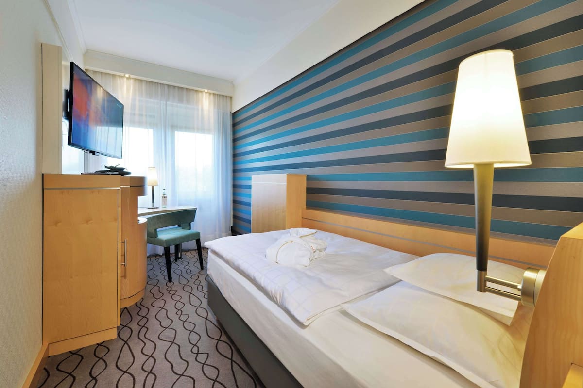 Une chambre d’hôtel avec un lit, un bureau, une télévision et une lampe.