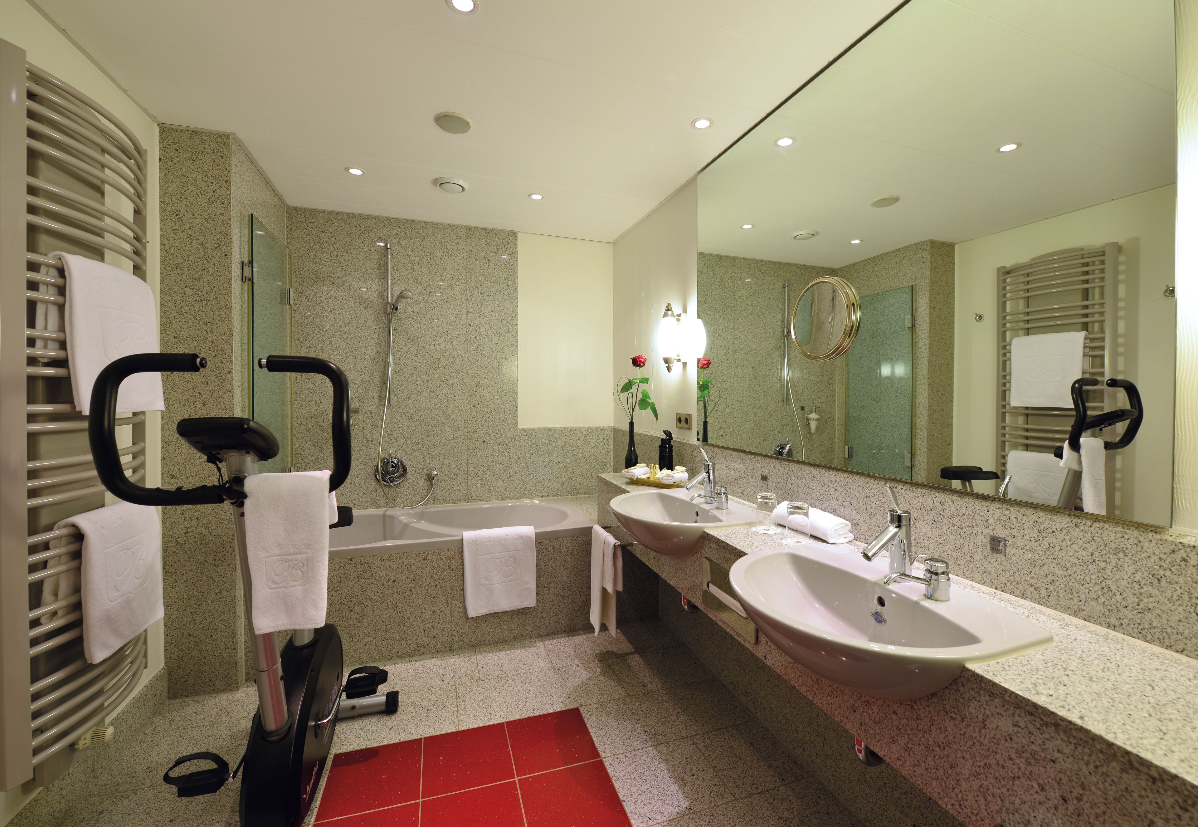 Une salle de bain moderne avec un meuble-lavabo à deux vasques, un grand miroir, un espace douche et un sol carrelé de carreaux rouges.
