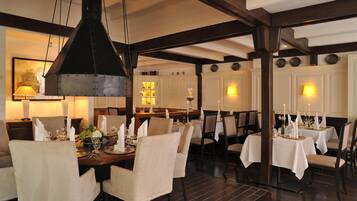 A dining area with tables set for service, chairs, and hanging light fixtures.