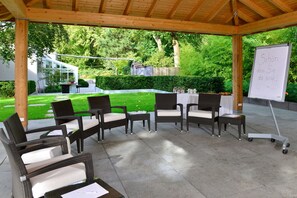 An outdoor patio area with wicker furniture, a whiteboard, and a table set for a meal. - Best Western Premier Parkhotel Kronsberg (Hannover)