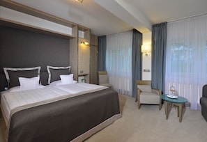 Een hotelkamer met een groot bed, een stoel, een tafeltje en een spiegel.