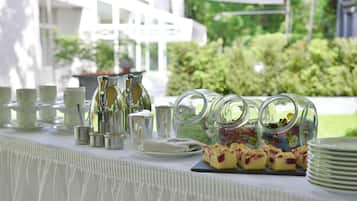 Ein reichhaltiges Buffet mit verschiedenen Speisen, darunter Süßigkeiten und Gebäck, sowie eine Auswahl an Tassen und kleinen Schalen.